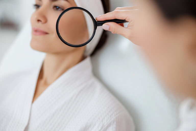 Beautician examining lady skin with magnifying glass