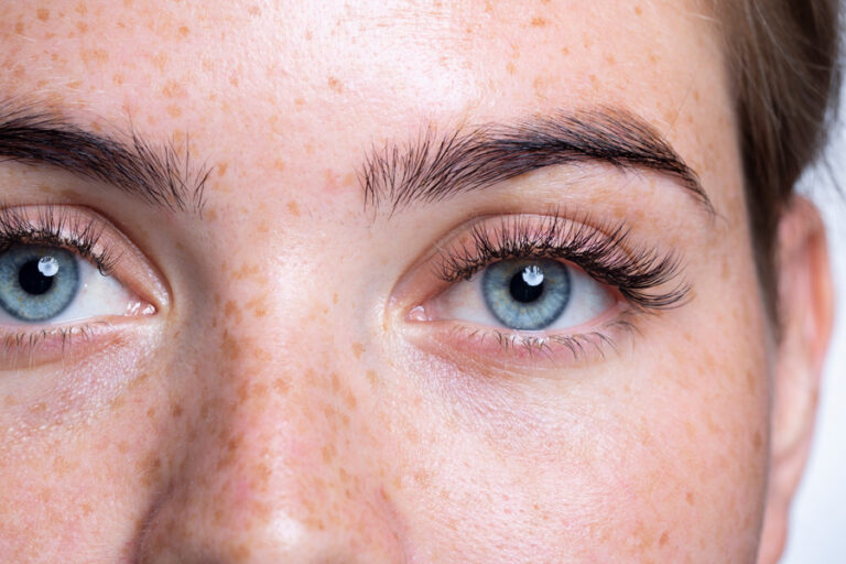 A close up of a person with blue eyes and think long eyelashes