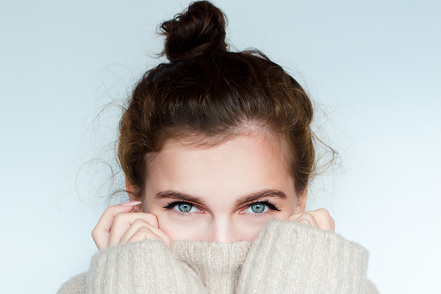 Winter portrait of a beautiful curly woman with blue eyes in a warm sweater