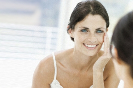 Woman checking her eyes and skin in the mirror