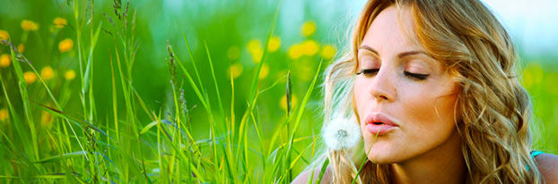 Woman on a field blowing a dandelion