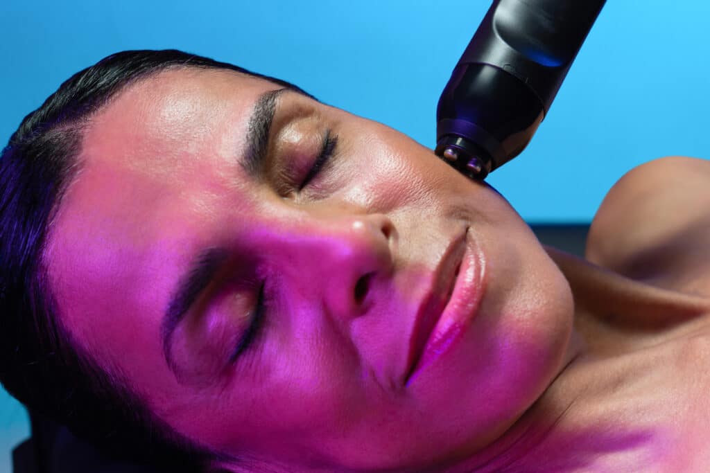 A Woman With Her Eyes Closed And A Glo2Facial Pen On Her Face