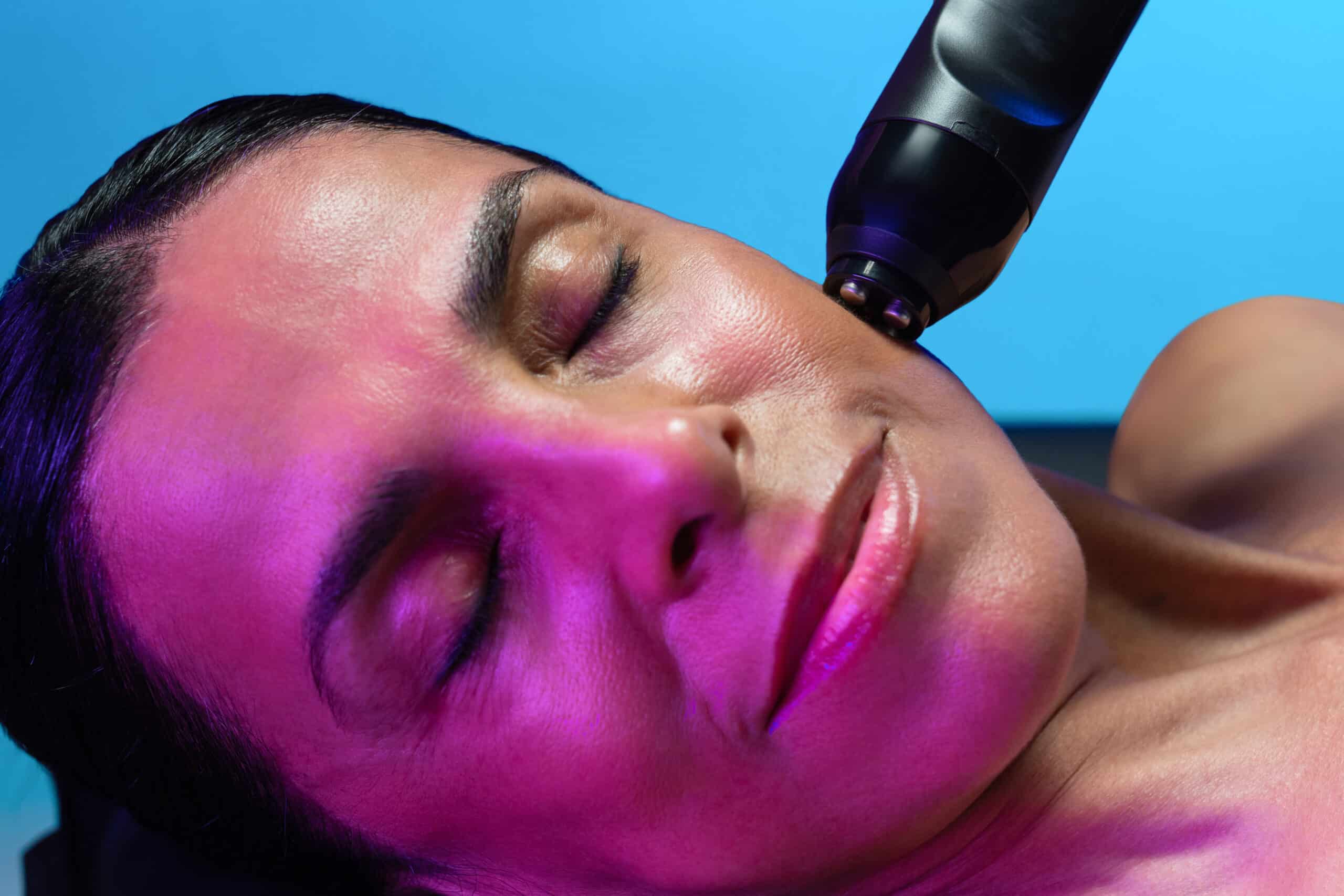 A Woman With Her Eyes Closed And A Glo2Facial Pen On Her Face