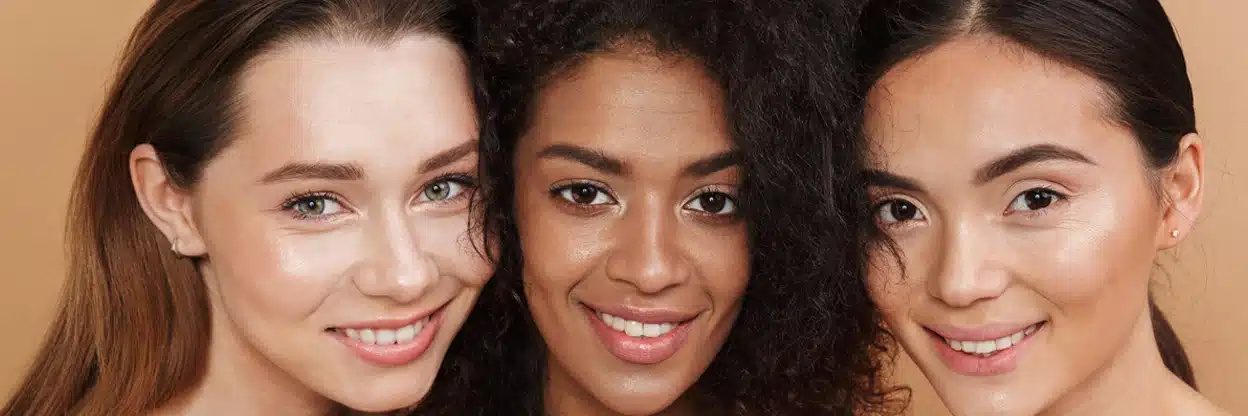 Three Diverse Individuals With Confident Smiles And Youthful Skin, Highlighting The Aesthetic Benefits Of Dysport Injections For A Younger Demographic.